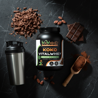 Koko VitalWhey Armour Reserve Belgian Chocolate flat lay with protein container, chocolate shavings, cacao beans and steel shaker on dark marble